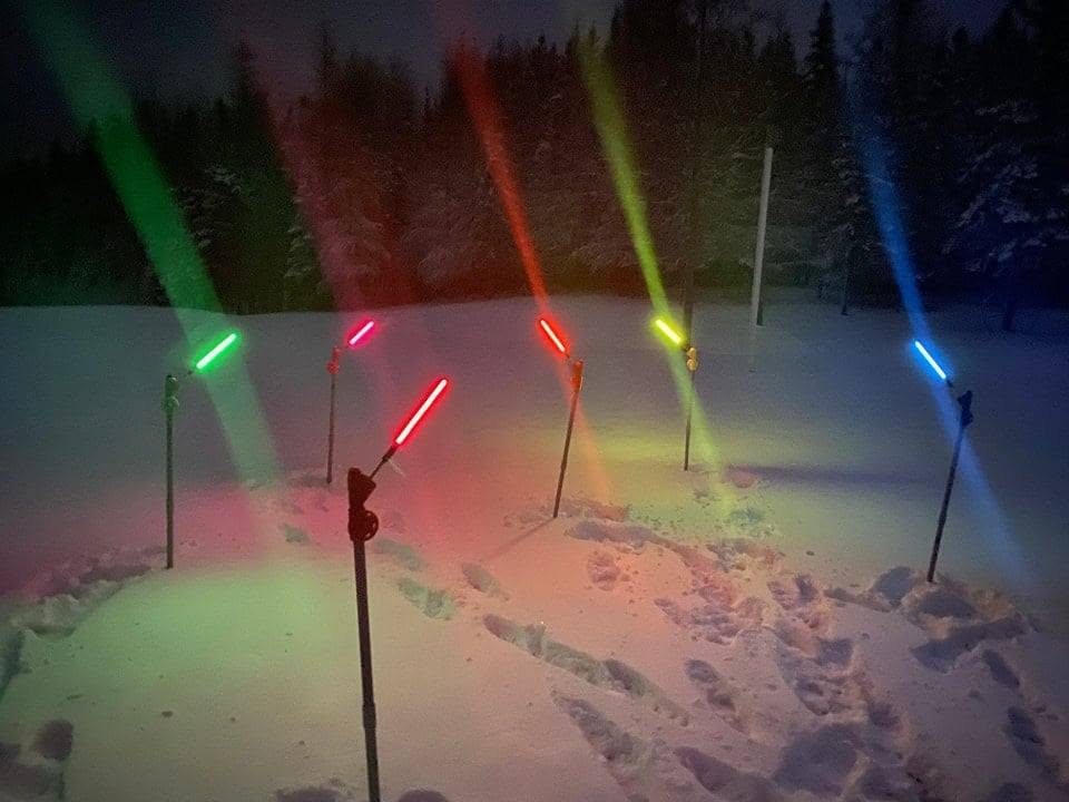 Six Chabite plantés dans la neige la nuit, chacun avec une tige BiteSaber allumée en vert, rouge, jaune ou bleu
